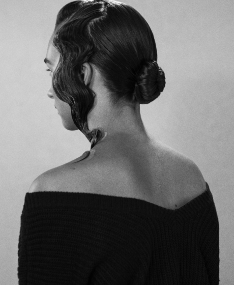 Black and white portrait of a woman's back showcasing a updo hair style